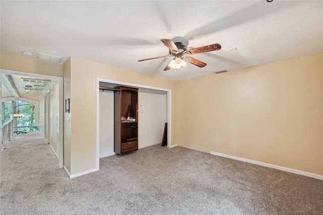 unfurnished bedroom featuring a textured ceiling, light colored carpet, a closet, and ceiling fan