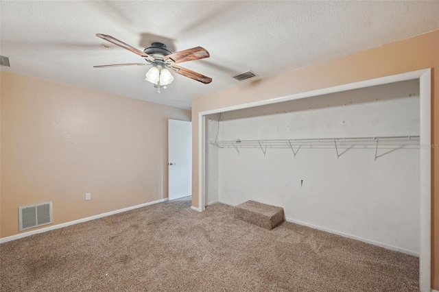 unfurnished bedroom featuring ceiling fan, a closet, carpet floors, and a textured ceiling