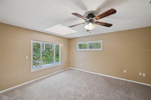 carpeted spare room with a textured ceiling, a skylight, and ceiling fan