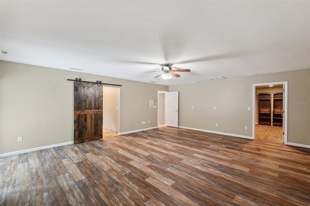 spare room with hardwood / wood-style floors, ceiling fan, and a barn door