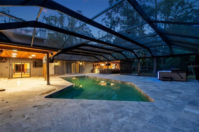 view of swimming pool featuring glass enclosure, a patio area, an outdoor bar, and a hot tub