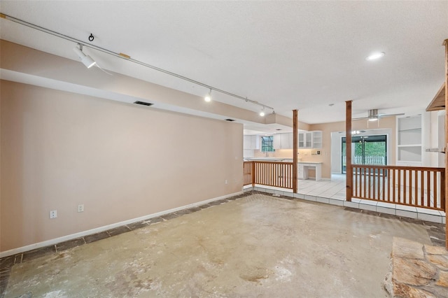 basement with a textured ceiling and track lighting