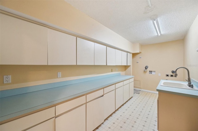 clothes washing area featuring sink, cabinets, a textured ceiling, and washer hookup