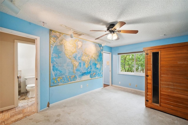 unfurnished bedroom featuring rail lighting, ensuite bath, a textured ceiling, light colored carpet, and ceiling fan