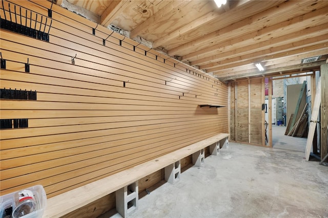 mudroom featuring wooden walls and concrete floors