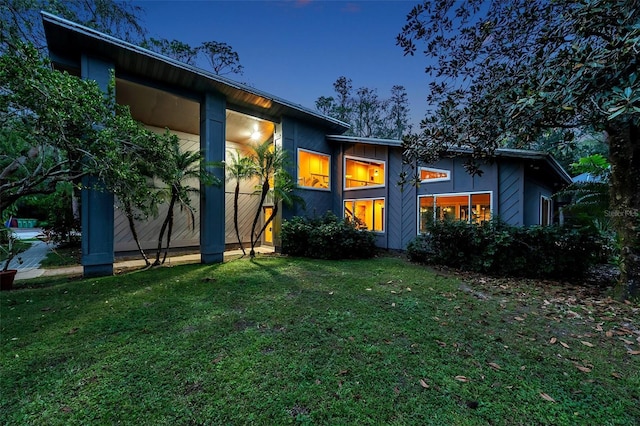 back house at dusk featuring a yard