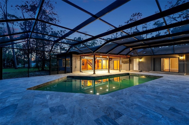 pool at dusk featuring glass enclosure and a patio