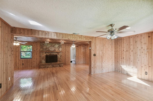 unfurnished living room with wood walls, a fireplace, wood-type flooring, and a textured ceiling