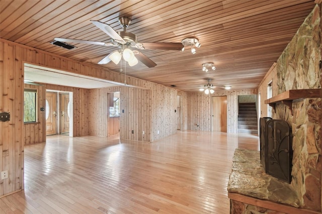 unfurnished living room featuring light wood-type flooring, wooden ceiling, and wood walls