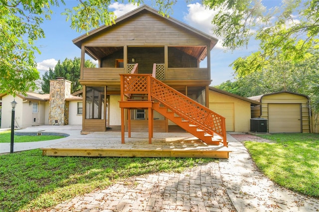 view of front of property featuring a sunroom, a deck, a front yard, central air condition unit, and a shed