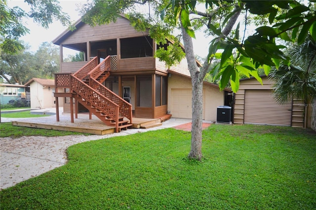 rear view of house with a lawn, a sunroom, cooling unit, and a garage