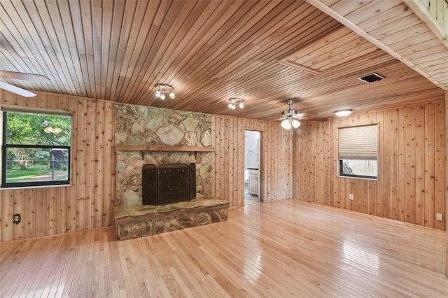 unfurnished living room featuring wood walls, plenty of natural light, and wood ceiling