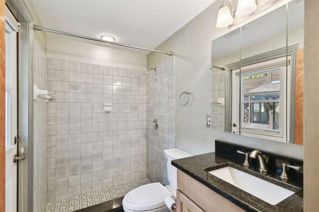 bathroom with a tile shower, vanity, and toilet