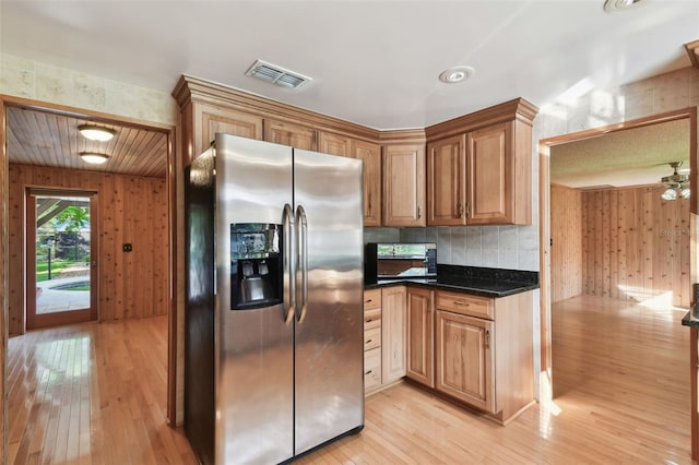 kitchen with stainless steel fridge, ceiling fan, wood walls, and light wood-type flooring