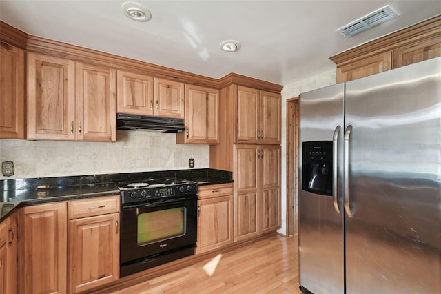 kitchen with stainless steel refrigerator with ice dispenser, light hardwood / wood-style flooring, decorative backsplash, dark stone countertops, and gas stove