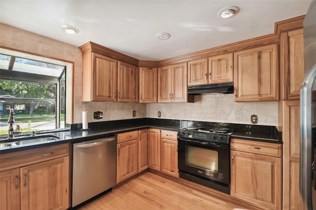 kitchen with dark stone counters, black range, sink, light hardwood / wood-style flooring, and stainless steel dishwasher