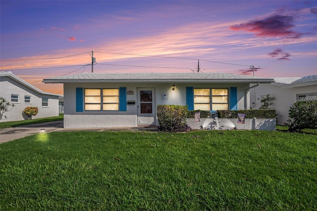 view of front of home featuring stucco siding and a yard