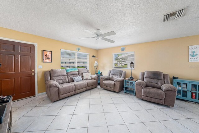 living area featuring a ceiling fan, light tile patterned floors, a textured ceiling, and visible vents