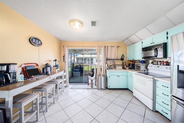 kitchen featuring a textured ceiling, lofted ceiling, light tile patterned flooring, and electric range