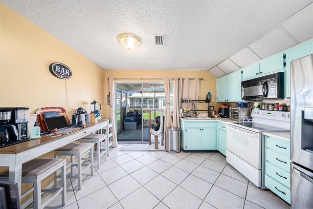 kitchen featuring visible vents, white electric stove, black microwave, blue cabinets, and vaulted ceiling