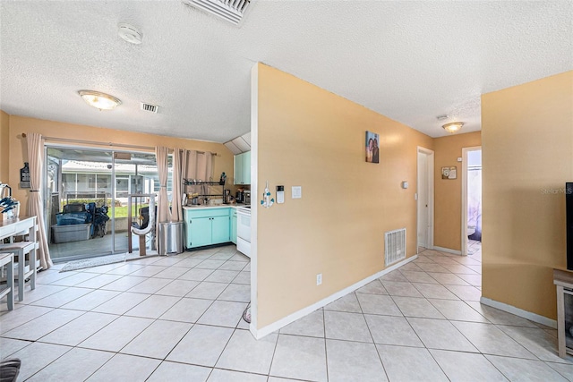 kitchen with a textured ceiling, lofted ceiling, light tile patterned floors, and white range