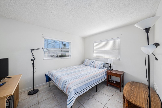 bedroom featuring light tile patterned flooring, baseboards, and a textured ceiling