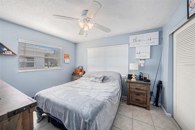 bedroom featuring ceiling fan, a textured ceiling, and light tile patterned flooring