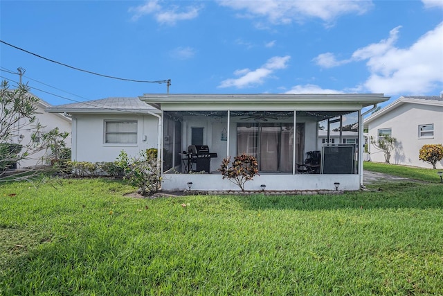 rear view of property with a sunroom, stucco siding, and a yard