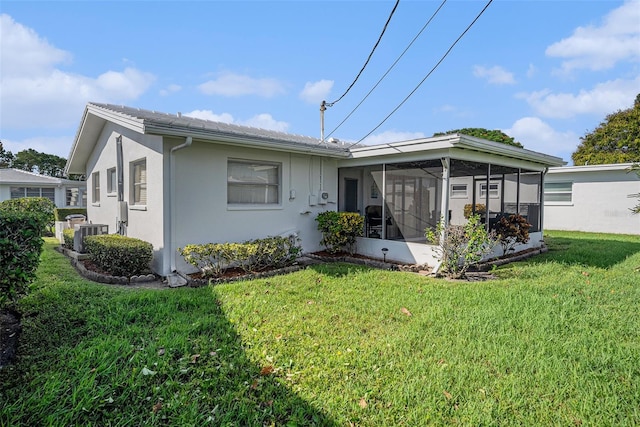 view of front facade featuring a sunroom, stucco siding, central air condition unit, and a front lawn