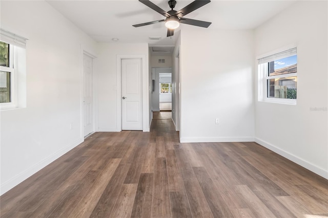 empty room with ceiling fan, plenty of natural light, and dark hardwood / wood-style flooring