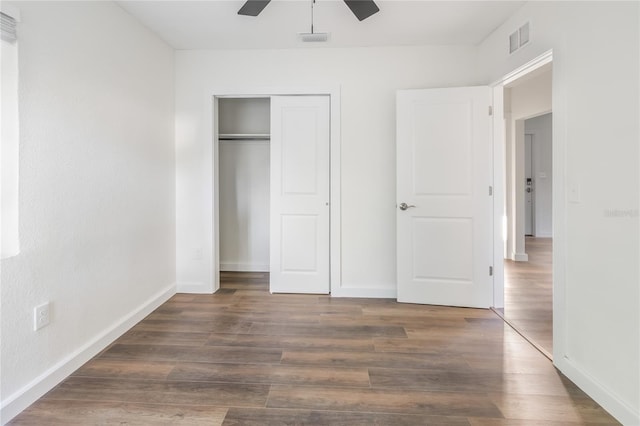 unfurnished bedroom featuring dark hardwood / wood-style flooring, ceiling fan, and a closet