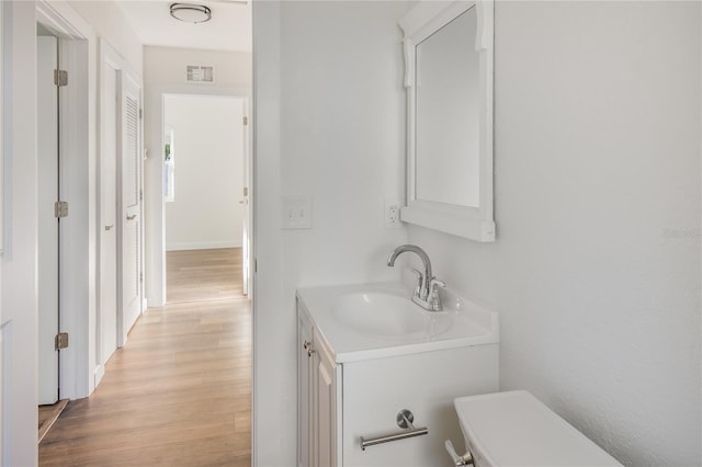 bathroom with vanity, toilet, and hardwood / wood-style flooring