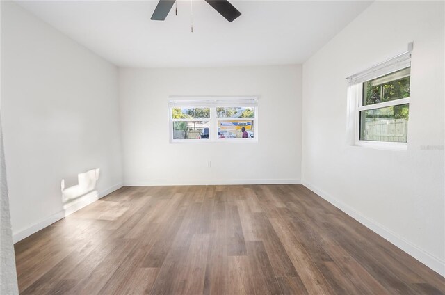 empty room with dark wood-type flooring, ceiling fan, and a wealth of natural light