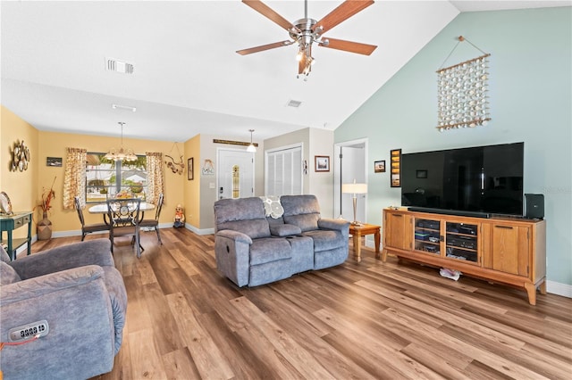 living room with vaulted ceiling, wood-type flooring, and ceiling fan with notable chandelier