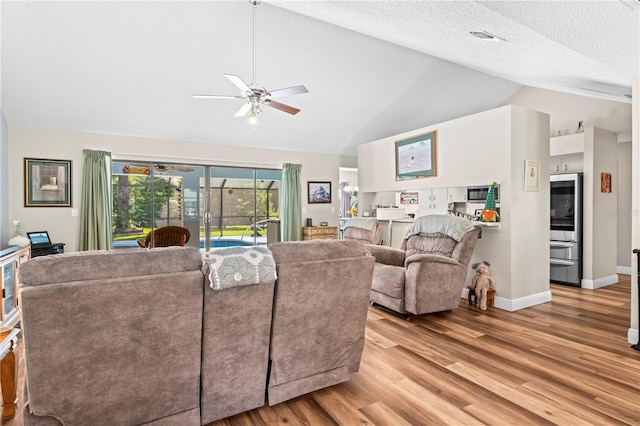 living room featuring ceiling fan, light hardwood / wood-style flooring, high vaulted ceiling, and a textured ceiling