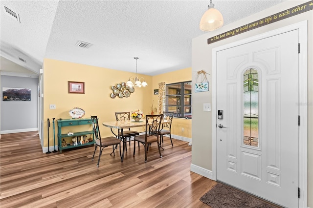 foyer entrance with a textured ceiling, hardwood / wood-style flooring, and an inviting chandelier