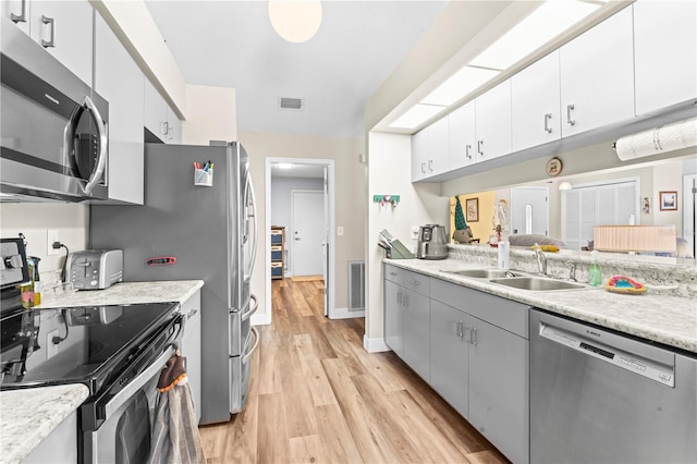 kitchen featuring appliances with stainless steel finishes, light hardwood / wood-style floors, white cabinetry, and sink