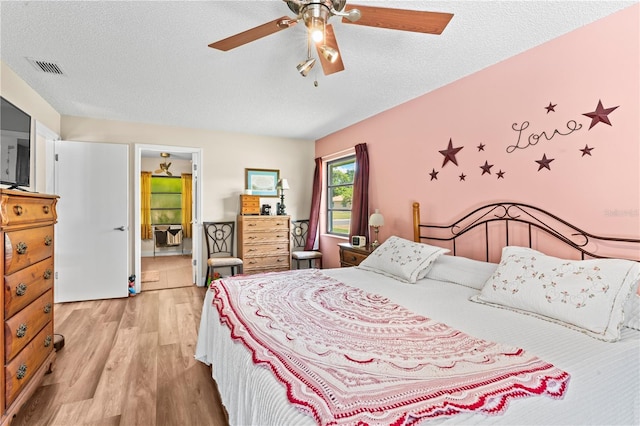 bedroom with ceiling fan, light hardwood / wood-style flooring, and a textured ceiling