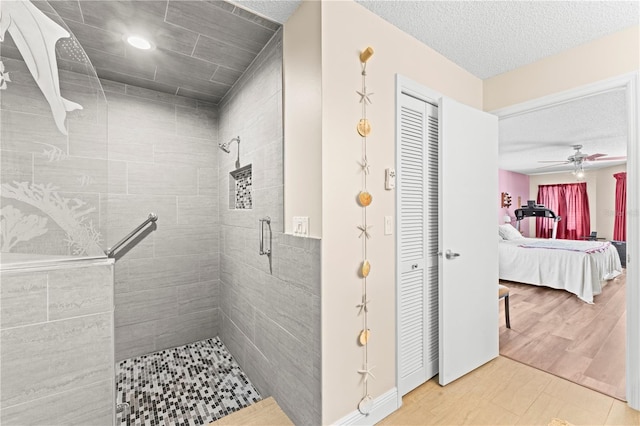 bathroom featuring hardwood / wood-style floors, ceiling fan, an enclosed shower, and a textured ceiling