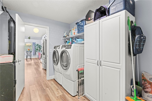 clothes washing area featuring light wood-type flooring, independent washer and dryer, and a textured ceiling