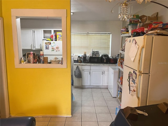 kitchen featuring white cabinets, washer / clothes dryer, light tile patterned flooring, and white fridge