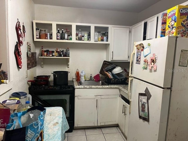 kitchen featuring black / electric stove, light tile patterned flooring, white cabinets, white refrigerator, and sink