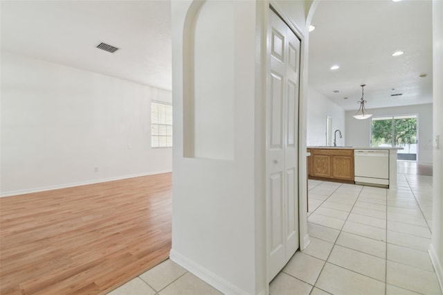 corridor with light wood-type flooring and sink