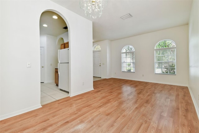 empty room featuring light wood-type flooring and a chandelier