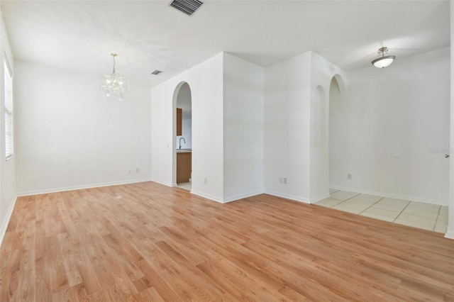 empty room with a chandelier and light hardwood / wood-style floors