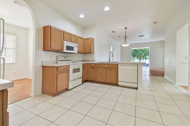 kitchen featuring light wood-type flooring, sink, kitchen peninsula, white appliances, and decorative light fixtures