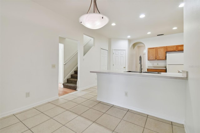 kitchen featuring white refrigerator, hanging light fixtures, sink, and light tile patterned flooring