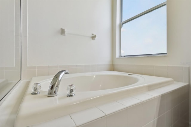 bathroom with a relaxing tiled tub and a healthy amount of sunlight