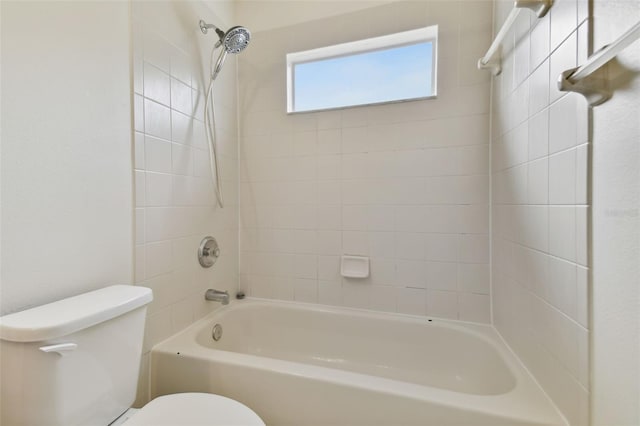 bathroom with tiled shower / bath combo and toilet