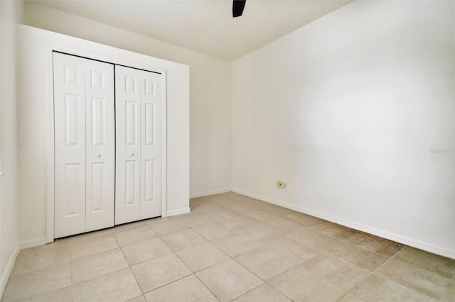 unfurnished bedroom with light tile patterned floors, ceiling fan, and a closet